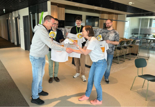 A group of five employees stand in a modern office social area during a Coding4U event.