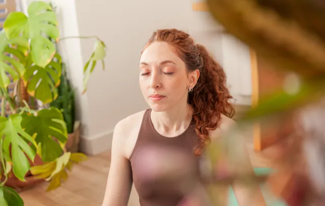 Quiet moment at work: person sitting near plants in a calm, light-filled space