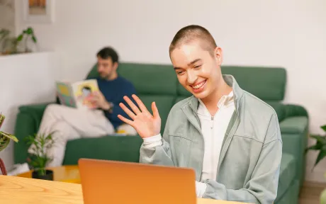 Person smiling and waving at laptop. 